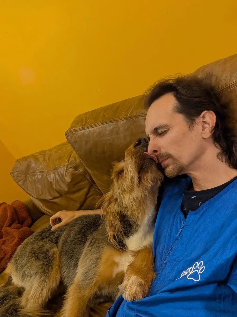 A dog giving Gary an affectionate nuzzle at Sweet Beans Grooming